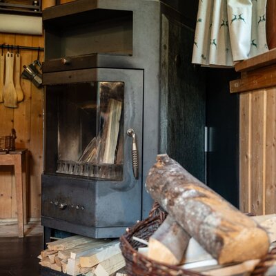 Ein gemütlicher Kaminofen in der Alm mit bereitgelegtem Brennholz für behagliche Wärme.