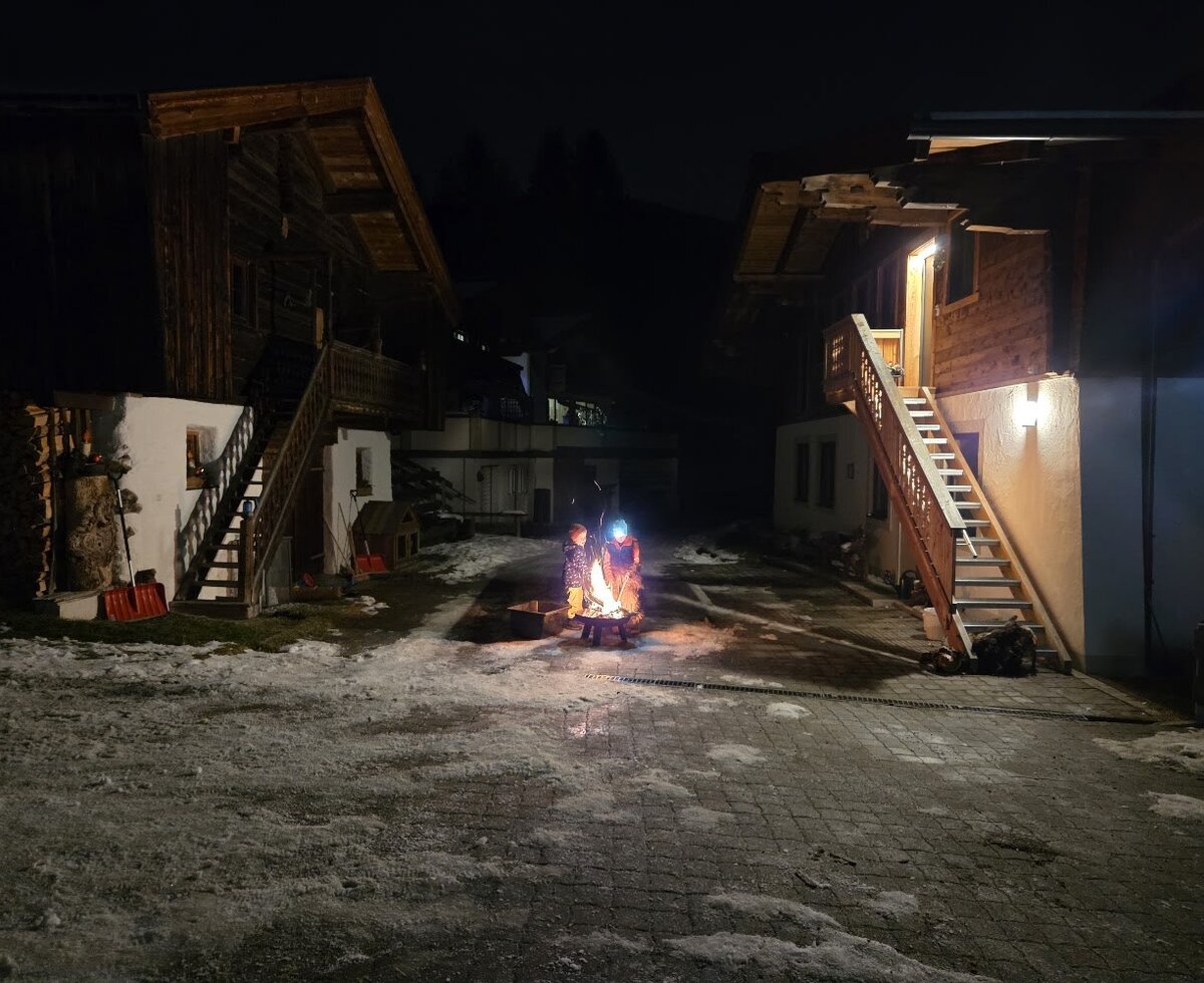 Ein gemütliches Lagerfeuer im verschneiten Hof des Bauernhofs bei Nacht.
