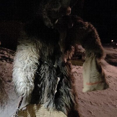 Eine traditionelle Krampus-Figur im verschneiten Außenbereich des Bauernhofs.