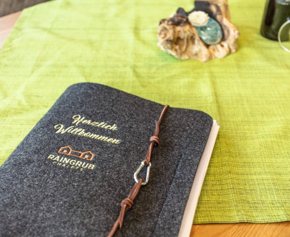 Eine Willkommensmappe aus Filz für Gäste mit der Aufschrift „Herzlich Willkommen“ auf einem Tisch im Hof.