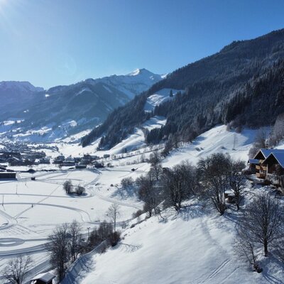 Blick auf den Bauernhof, das verschneite Tal und die umliegenden Berge.