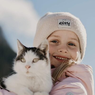 Ein lächelndes Kind hält eine Katze, ein typisches Bild auf dem Bauernhof.