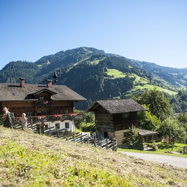 Der Bauernhof in traditioneller Holzbauweise mit weitem Blick auf die umliegenden Berge und das Tal.