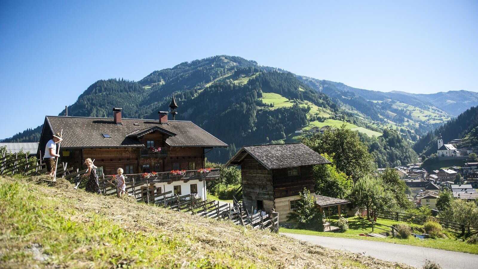 Der Bauernhof in traditioneller Holzbauweise mit weitem Blick auf die umliegenden Berge und das Tal.