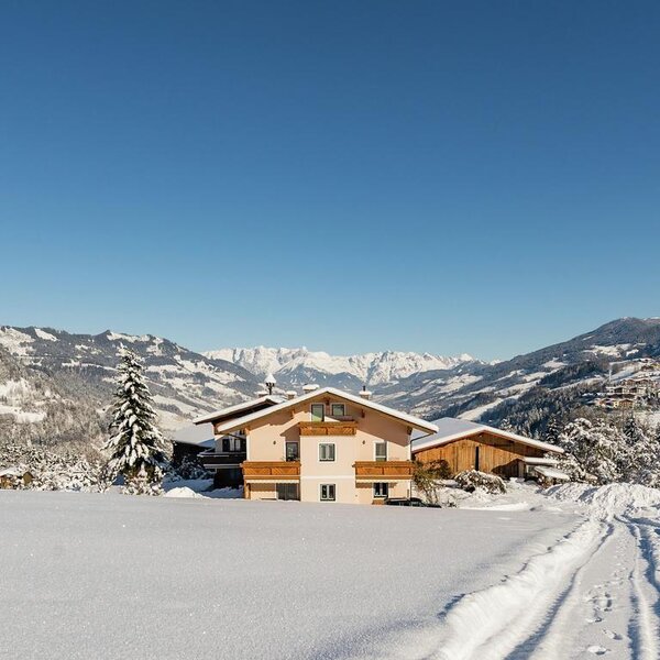 Der Bauernhof in einer verschneiten Winterlandschaft mit Blick auf die Berge.
