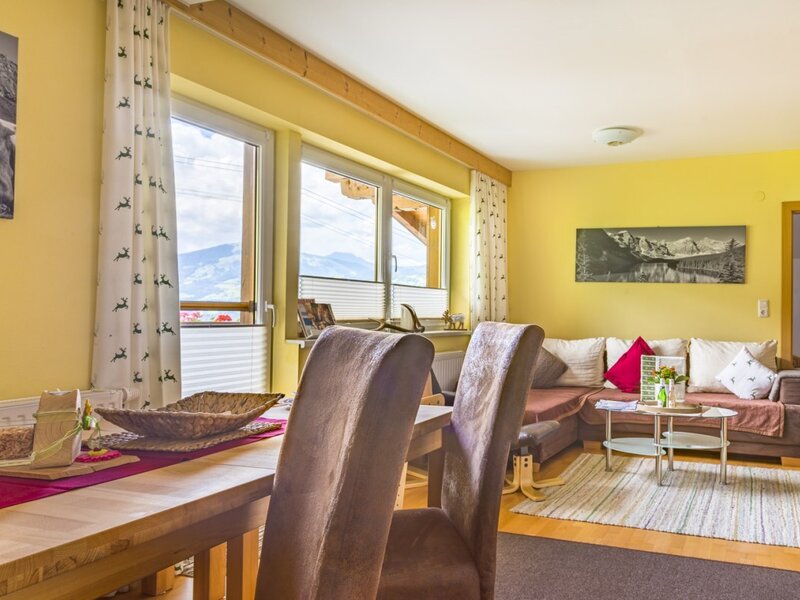 Der Wohn- und Essbereich des Bauernhofs verfügt über einen Esstisch, ein Sofa, einen Fernseher und Fenster mit Bergblick.