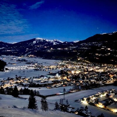 Atemberaubende Aussicht auf die schneebedeckte Stadt Mittersill und dem Salzachtal bei Nacht.