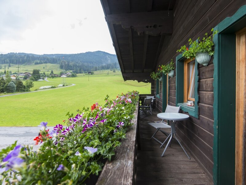 Balkon des Bauernhofs mit Blumenkästen, Sitzgelegenheiten und Blick auf die grüne Landschaft.