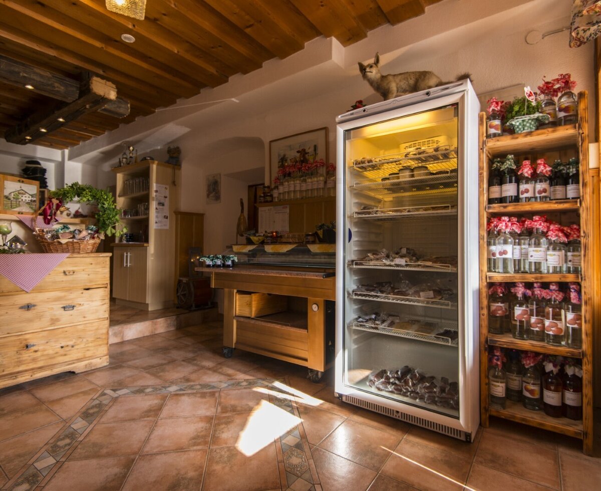 Der Verkaufsbereich im Bed and Breakfast mit einem Kühlschrank für Produkte und einem Holzregal mit Flaschengetränken.