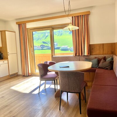 Offener Wohnbereich im Bauernhof mit voll ausgestatteter Küche, Essbereich mit Eckbank und Zugang zum Balkon mit Bergblick.