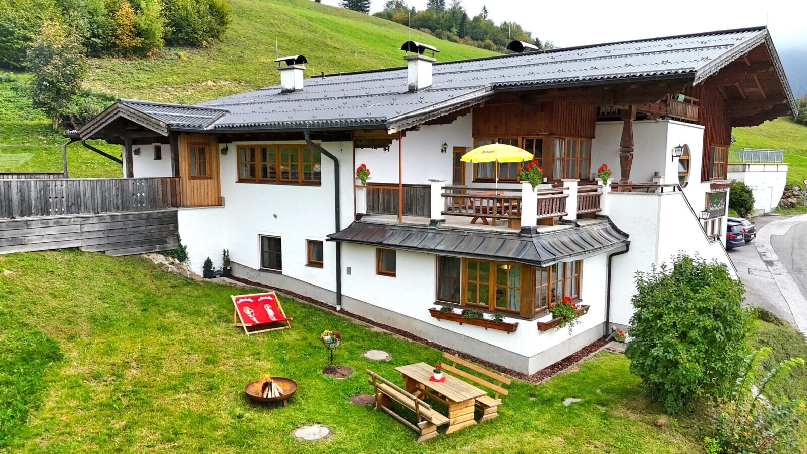 Die charmante Ferienwohnung mit einem gepflegten Garten, einer gemütlichen Sitzecke und einer einladenden Terrasse vor einer grünen Hügelkulisse.