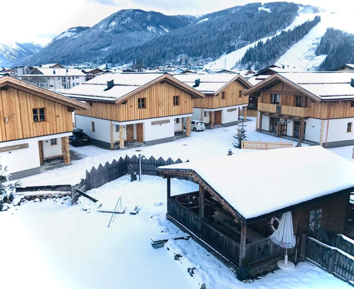 Die Gebäude des Bauernhofs im Winter, umgeben von schneebedeckten Bergen und mit Blick auf die Skipisten.