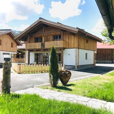 Außenansicht des Bauernhofs mit Holzfassade, Balkon und Gartenbereich.