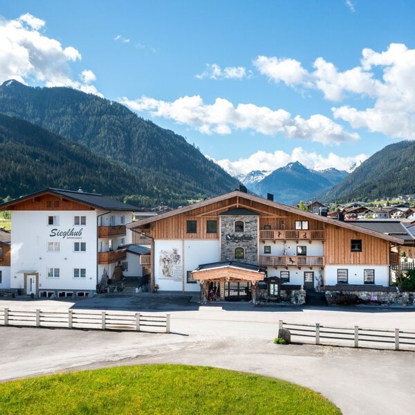 Der Bauernhof Sieglhub mit traditioneller Holz- und Putzfassade, Balkonen und der umliegenden Berglandschaft.