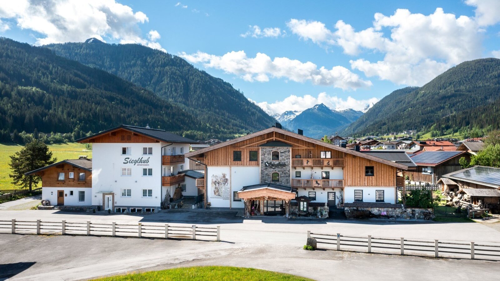 Der Bauernhof Sieglhub mit traditioneller Holz- und Putzfassade, Balkonen und der umliegenden Berglandschaft.