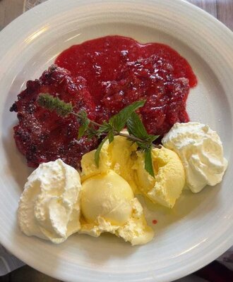 Dessert mit Beerensoße, Vanilleeis, Schlagsahne und Minzgarnitur, als Speiseangebot im Bauernhof.