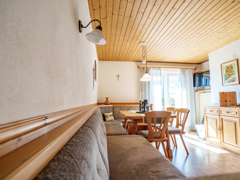 Essbereich der Ferienwohnung im Bauernhof mit Holztisch, Eckbank und Zugang zum Balkon.