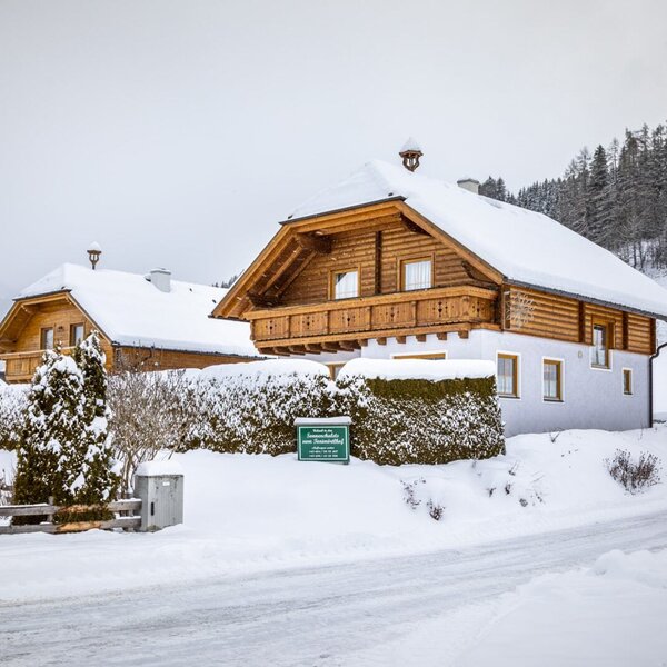 Die Sonnenchalets im Winter, mit schneebedeckten Dächern, Holzbalkonen und der umgebenden Winterlandschaft.