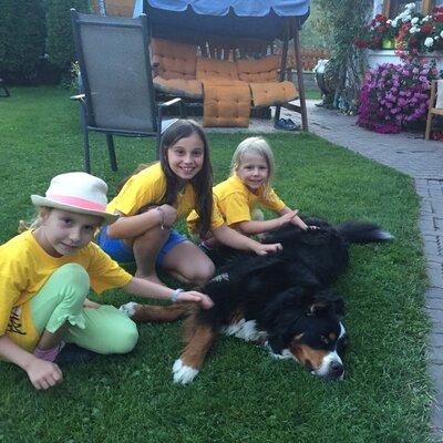 Drei Kinder streicheln einen Hund im Garten des Bauernhofs.