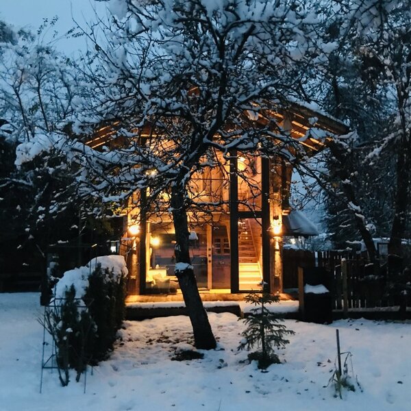 Der Hof bei Nacht im Schnee, mit beleuchtetem Inneren und schneebedeckten Bäumen.