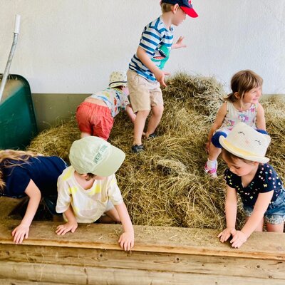 Fröhliche Kinder beim ausgelassenen Spielen im duftenden Heu auf dem Bauernhof.