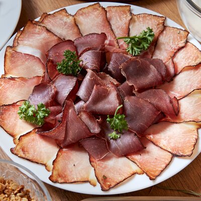 Eine Platte mit verschiedenen Wurst- und Schinkensorten, angeboten auf dem Bauernhof.