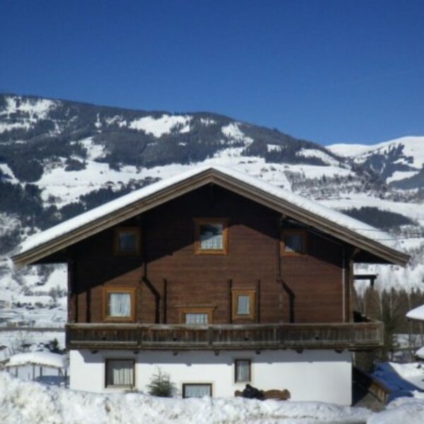 Der Bauernhof im Winter, umgeben von Schnee und schneebedeckten Bergen mit Talblick.