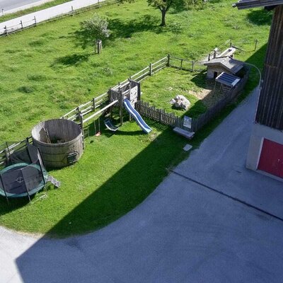 Der Kinderspielplatz auf dem Bauernhof umfasst eine Rutsche, Schaukeln, Kletterwand, ein Trampolin und ein großes Holzfass.