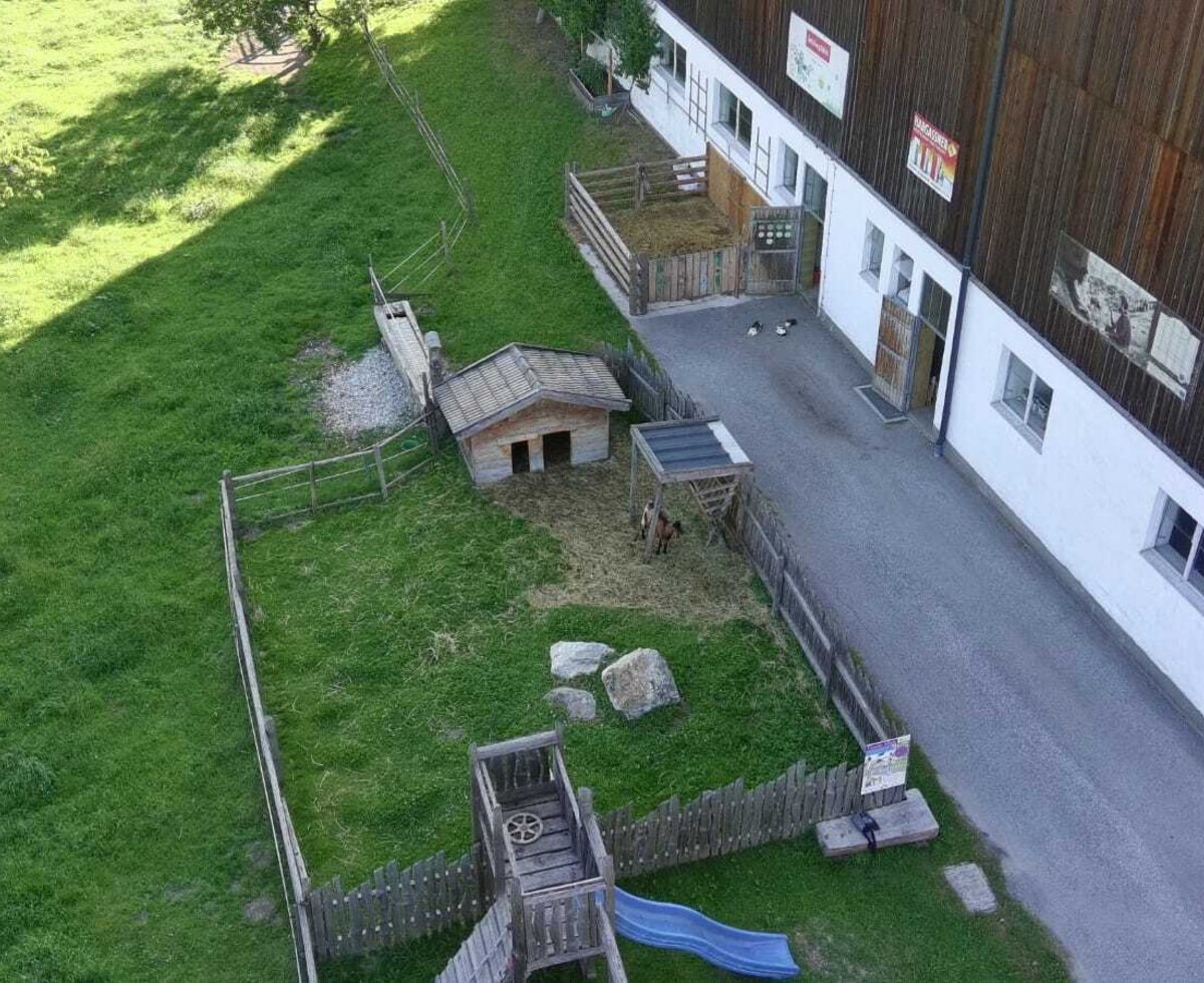 Im Außenbereich des Bauernhofs gibt es einen Kinderspielplatz mit Rutsche und einen Tierbereich mit Ziegen.