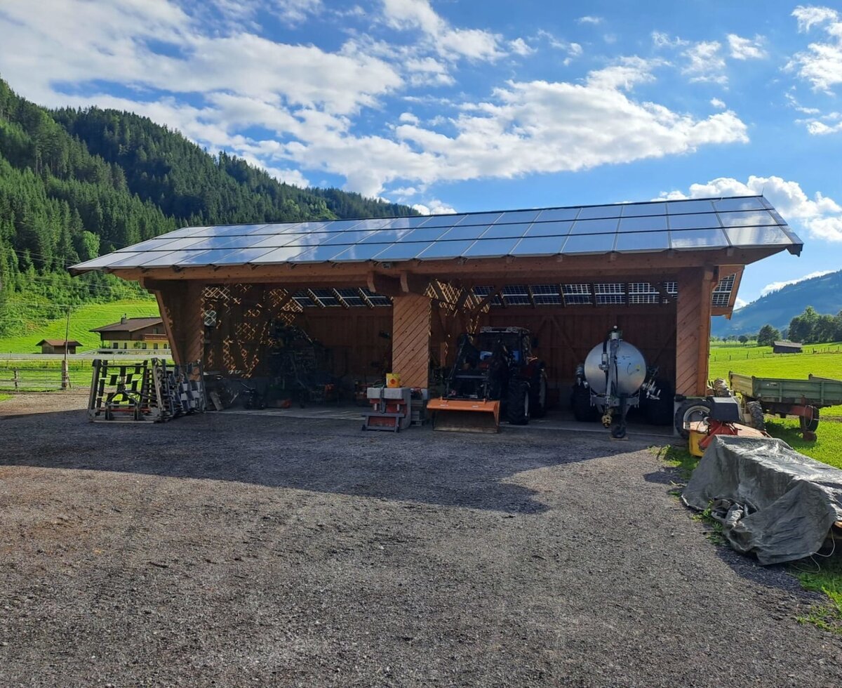Die Remise des Vierthalerhofs mit Solarpaneelen auf dem Dach und landwirtschaftlichen Geräten.