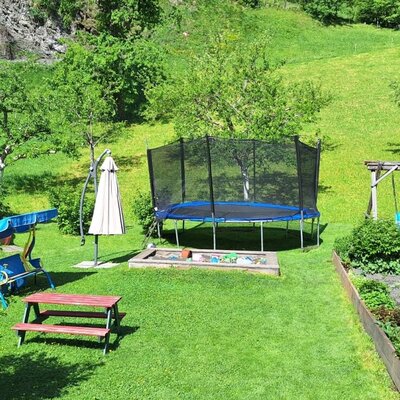 Der Garten der Ferienwohnung mit Kinderspielplatz, Trampolin, Rutschen, Schaukeln und Sandkasten.