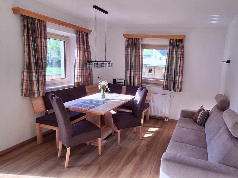 Wohn- und Essbereich der Ferienwohnung mit Esstisch, Eckbank, Stühlen und Sofa.