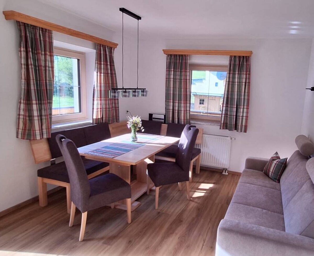 Wohn- und Essbereich der Ferienwohnung mit Esstisch, Eckbank, Stühlen und Sofa.