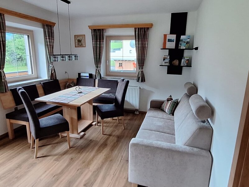 Der einladende Wohn- und Essbereich der Ferienwohnung mit einer gemütlichen Sitzecke, Holztisch und einem komfortablen Sofa.