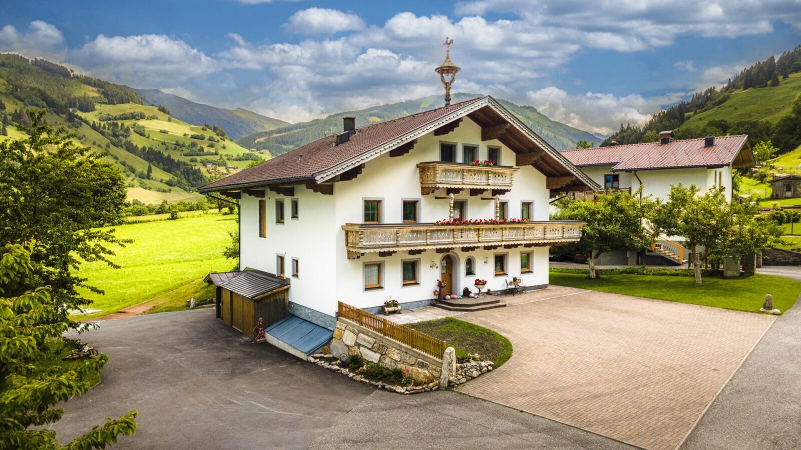 Das einladende Haus mit den Ferienwohnungen, umgeben von grünen Wiesen und einer malerischen Bergkulisse.