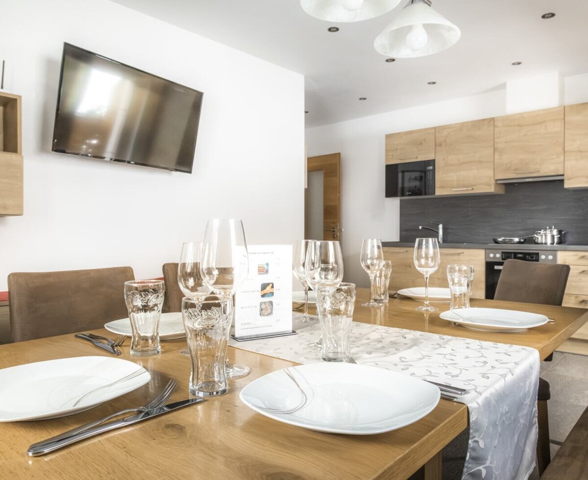 Der Essbereich mit gedecktem Tisch und Fernseher, angrenzend an die voll ausgestattete Küche.