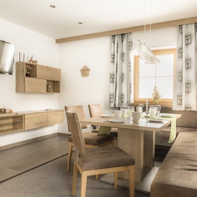 Essbereich mit Esstisch, Eckbank, Stühlen, Fernseher und Holzmöbeln.