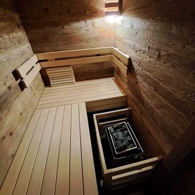 Die Sauna der Ferienwohnung mit Holzbänken und Saunaofen.