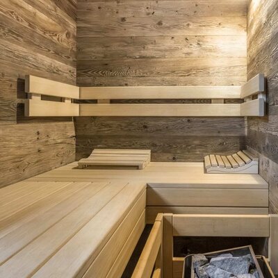 Sauna in der Ferienwohnung mit Holzwänden, Holzbänken und Saunaofen.