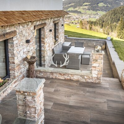 Die Terrasse der Ferienwohnung mit Outdoor-Sitzgruppe und Panoramablick auf das Tal und die umliegenden Berge.