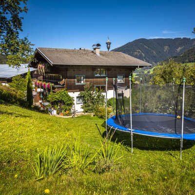 Das Trampolin im Garten des Bauernhofs bietet eine Freizeitmöglichkeit für Gäste mit Bergblick.