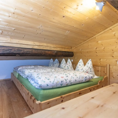Schlafzimmer mit Holzbett, floraler Bettwäsche und Holzverkleidung.