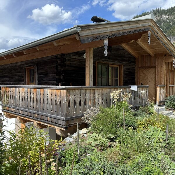 Die charmante Ferienwohnung im traditionellen Holzstil mit einem gemütlichen Balkon und üppiger Bepflanzung.