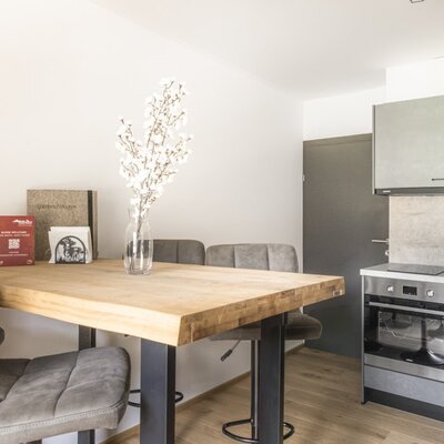Die Küche der Ferienwohnung mit Induktionsherd, Backofen, Geschirrspüler und einem Esstisch mit Stühlen.