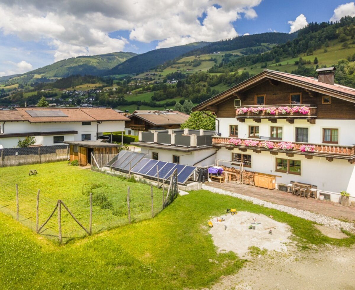 Das einladende Haus mit der Ferienwohnung bietet einen weitläufigen Garten, einen Sandkasten für Kinder und einen herrlichen Blick auf die umliegenden Berge.