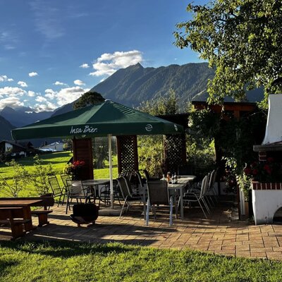 Die einladende Terrasse des Bauernhofs mit gemütlichen Sitzgelegenheiten, einem Grillkamin und Blick auf die umliegende Berglandschaft.