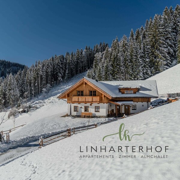 Der Hof in Alleinlage, umgeben von schneebedeckten Bergen und Wäldern im Winter.