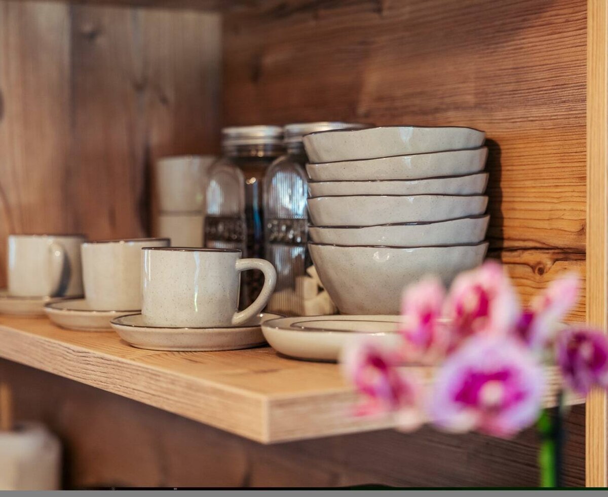 Geschirr wie Tassen, Untertassen und Schalen auf einem Holzregal .