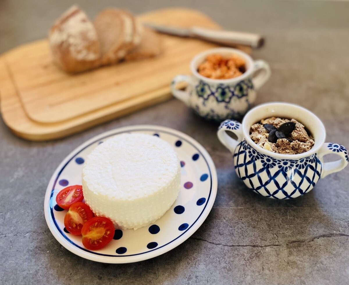 Ein köstliches Frühstück auf dem Bauernhof mit frischem Käse, Tomaten und hausgemachten Spezialitäten in traditionellem Geschirr.