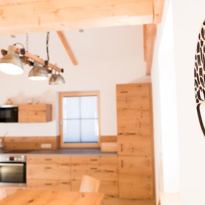 Die helle Wohnküche der Ferienwohnung mit modernen Holzmöbeln und stilvoller Wanddekoration.
